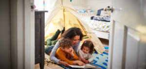 Single Mother Reading With Son And Daughter In Den In Bedroom At Home