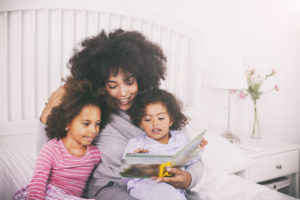 Mother reading books to daughters