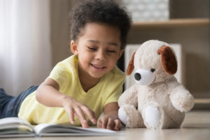 little boy reading to his stuffed puppy